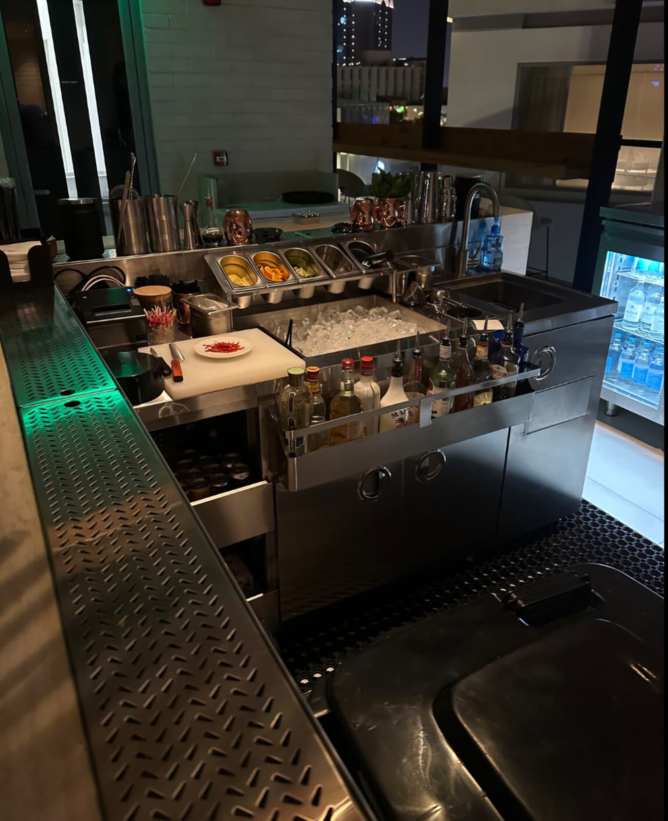 Stainless steel bar station with ice well, garnish tray, speed rail and drainboard at Orla