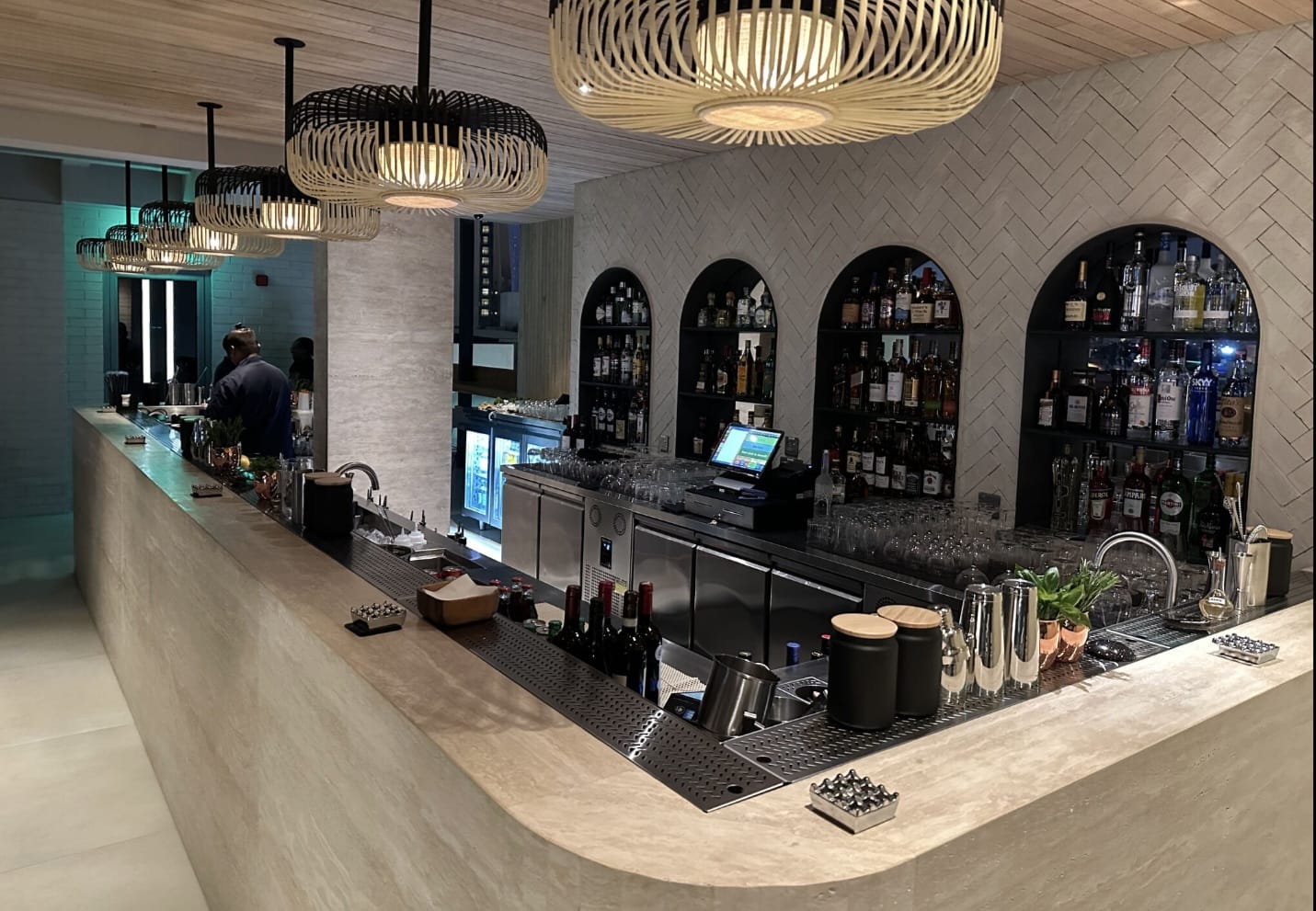 Curved stone-topped bar with stainless steel back bar and arched shelving at Orla