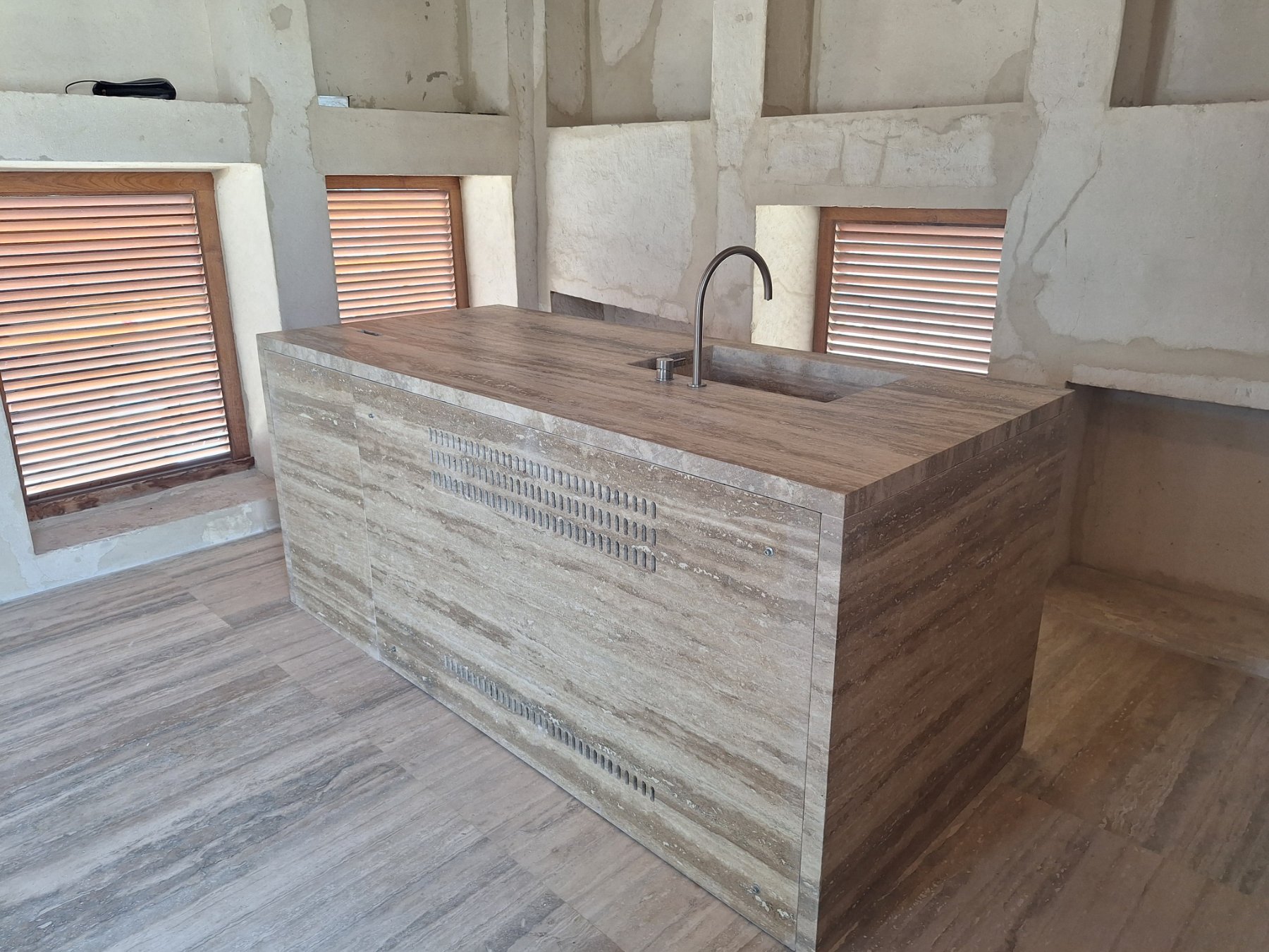 Travertine kitchen island with integrated stone sink and ventilated side panels