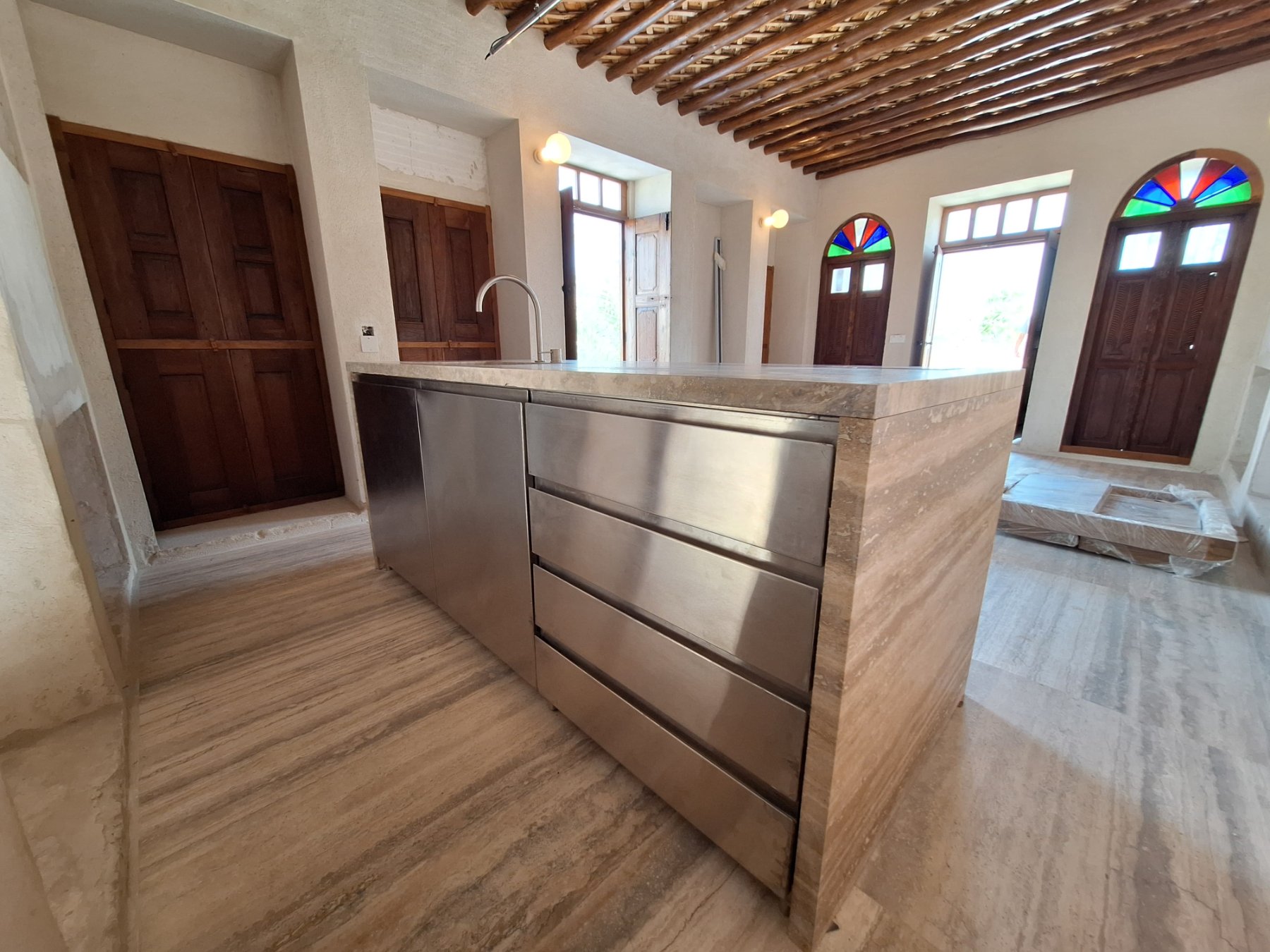 Kitchen island with stainless steel drawers in a traditional house with arched stained-glass doors